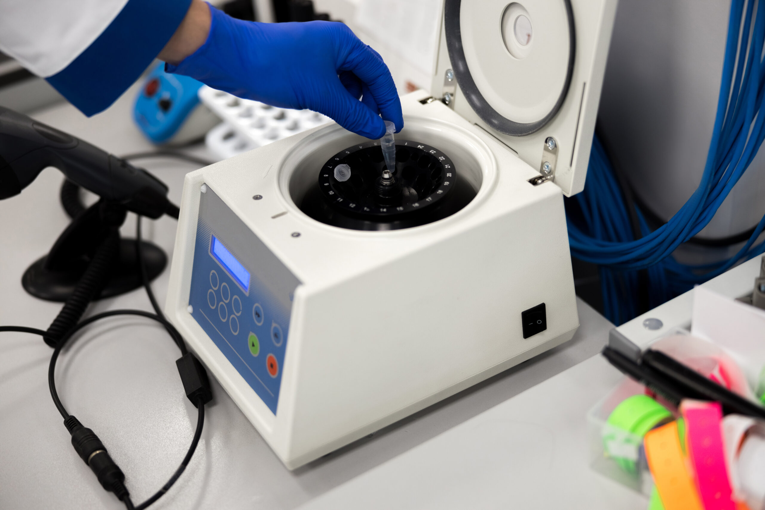 Close up of male researcher hand in sterile glove putting test tube into laboratory centrifuge stock photo